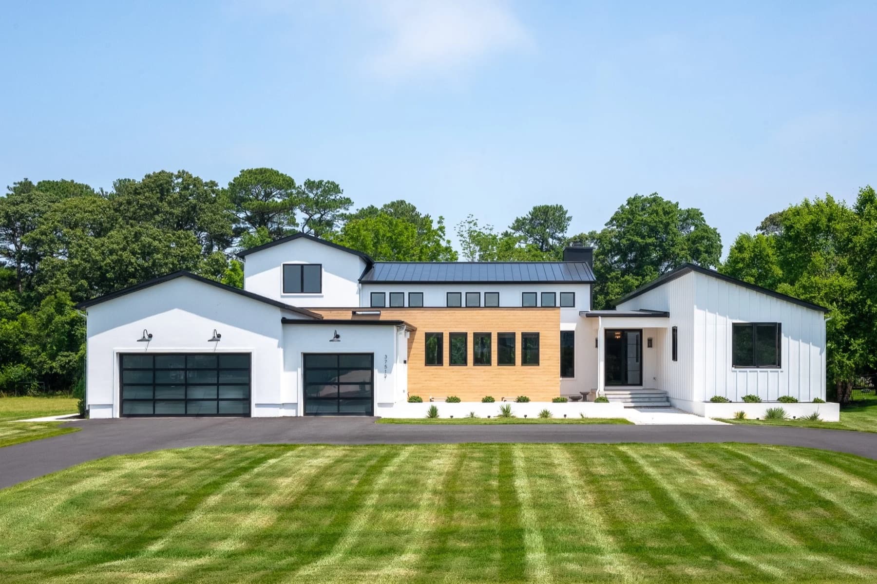 A single storey custom home with a cedar clad centre bay and black standing seam roof