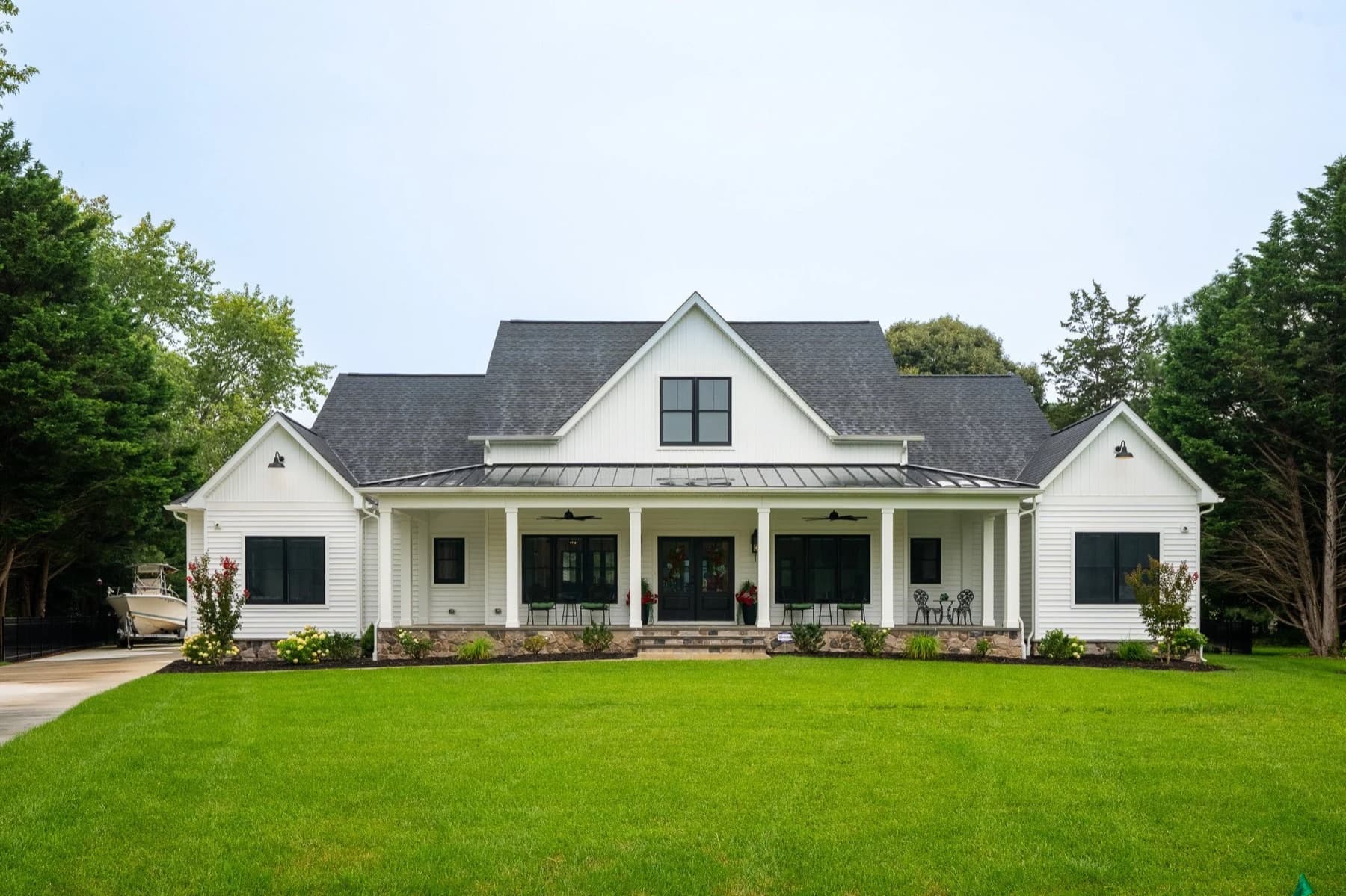 A cream and white farmhouse with dormers and a flag on the front porch